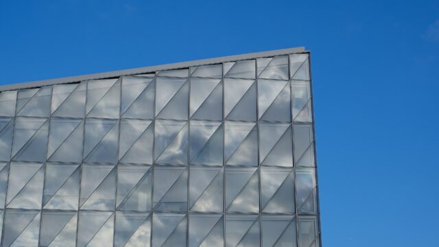 Glass exterior of JTI's headquarters in Geneva, Switzerland, against a blue sky