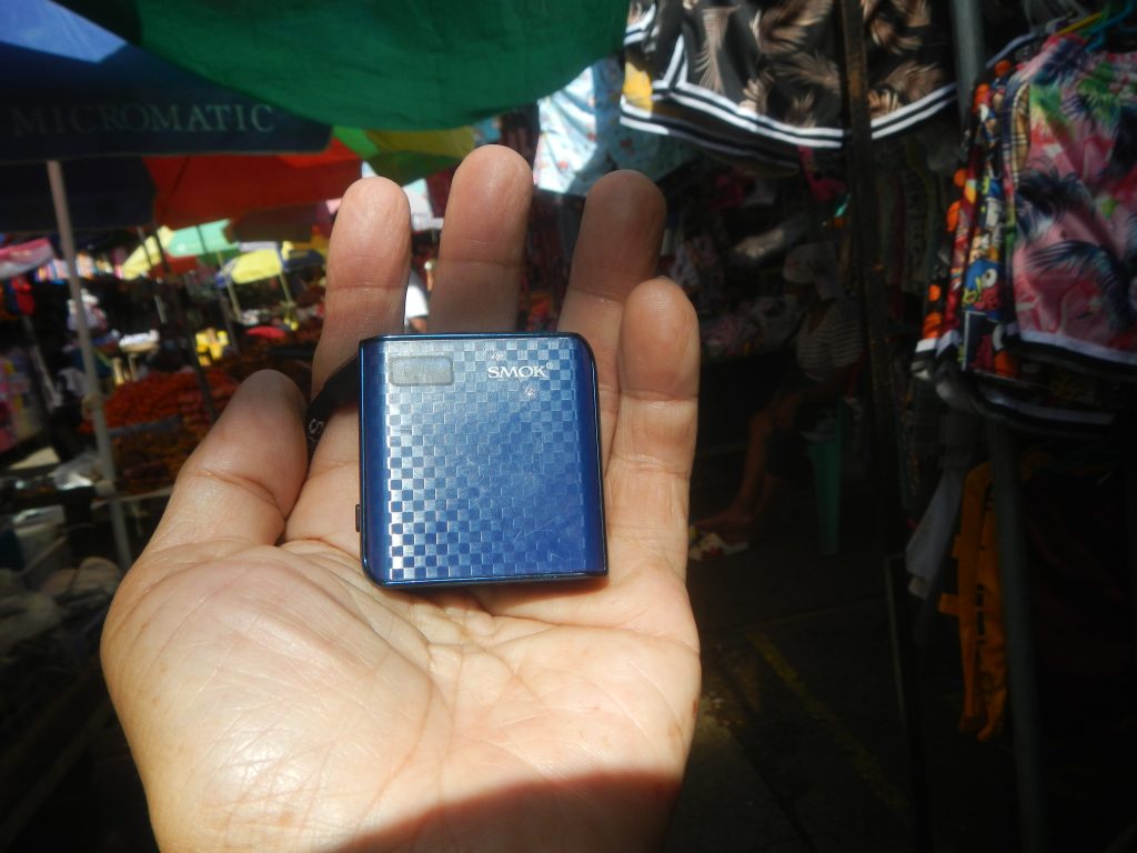 A blue square SMOK MICO device held in a hand, with the liquid window and side switch visible.